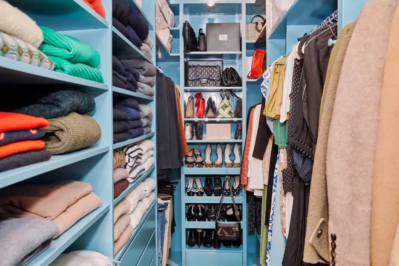 Opgeruimde kledingkast met gevouwen truien, tassen, schoenen en hangende kleding