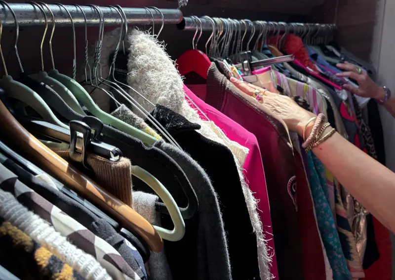 Handen gaan door een rek vol kleurrijke kleding