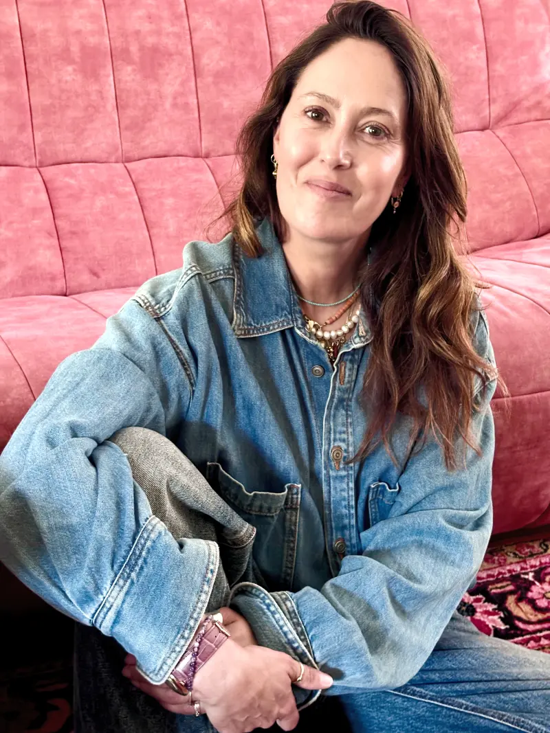 Portret van Sabine in een spijkerjack, zittend voor een roze bank